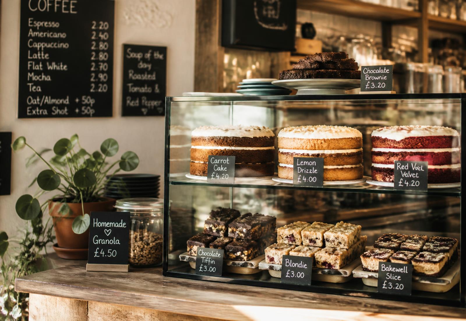 Independent coffee shop counter display filled with cakes, brownies and traybakes